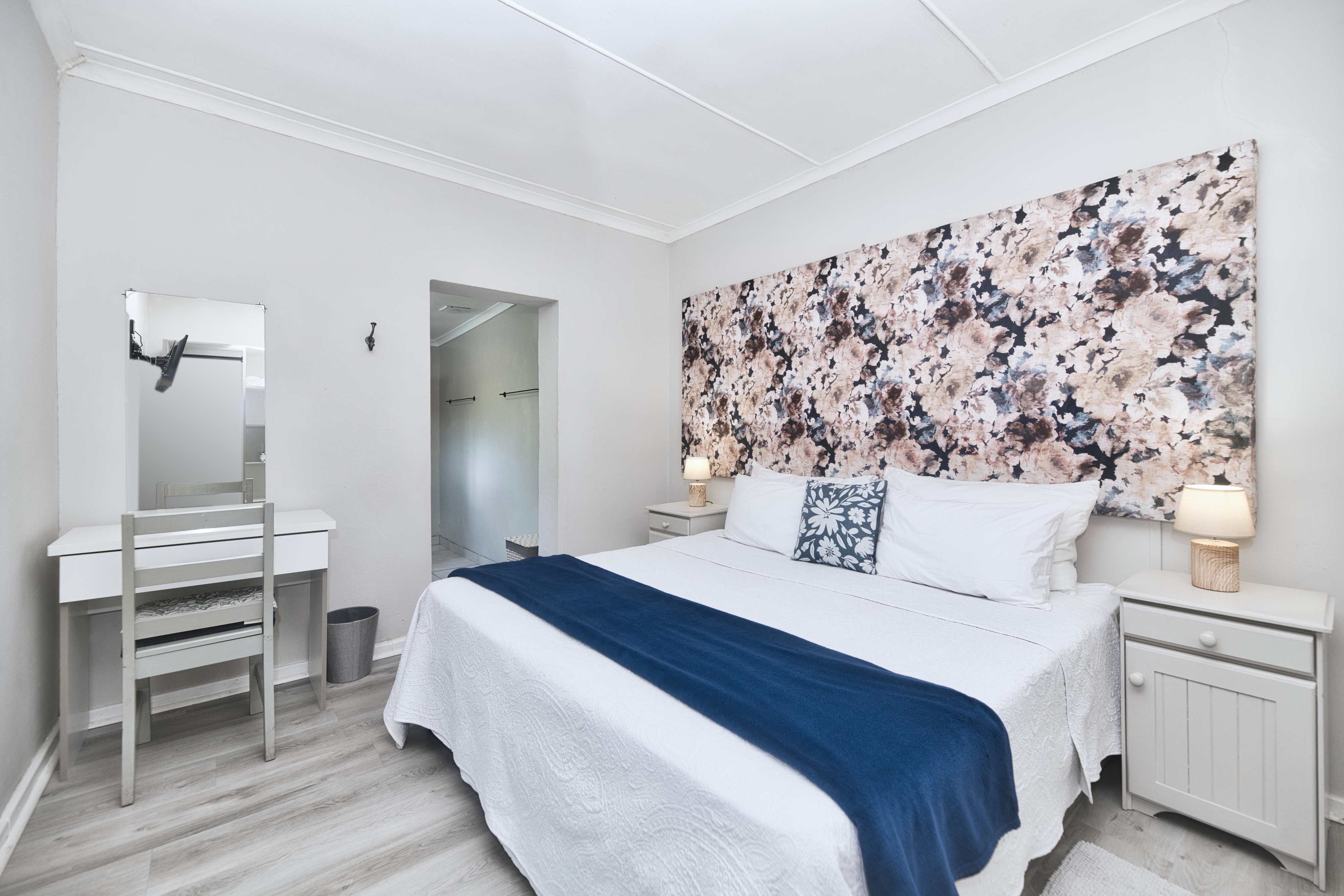 A calm, comfortable bedroom with crisp linen, soft lighting, and a beautiful statement headboard for that boutique-stay feel.